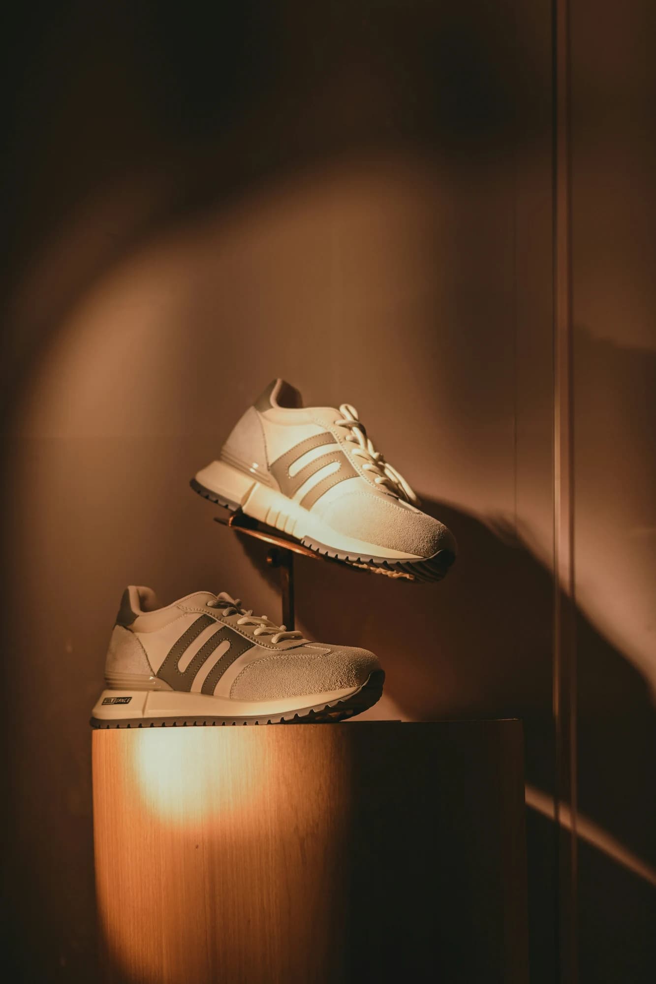 Sneakers on display stands under warm, focused lighting. — representative photo, not taken at 1Lux — St. Enoch