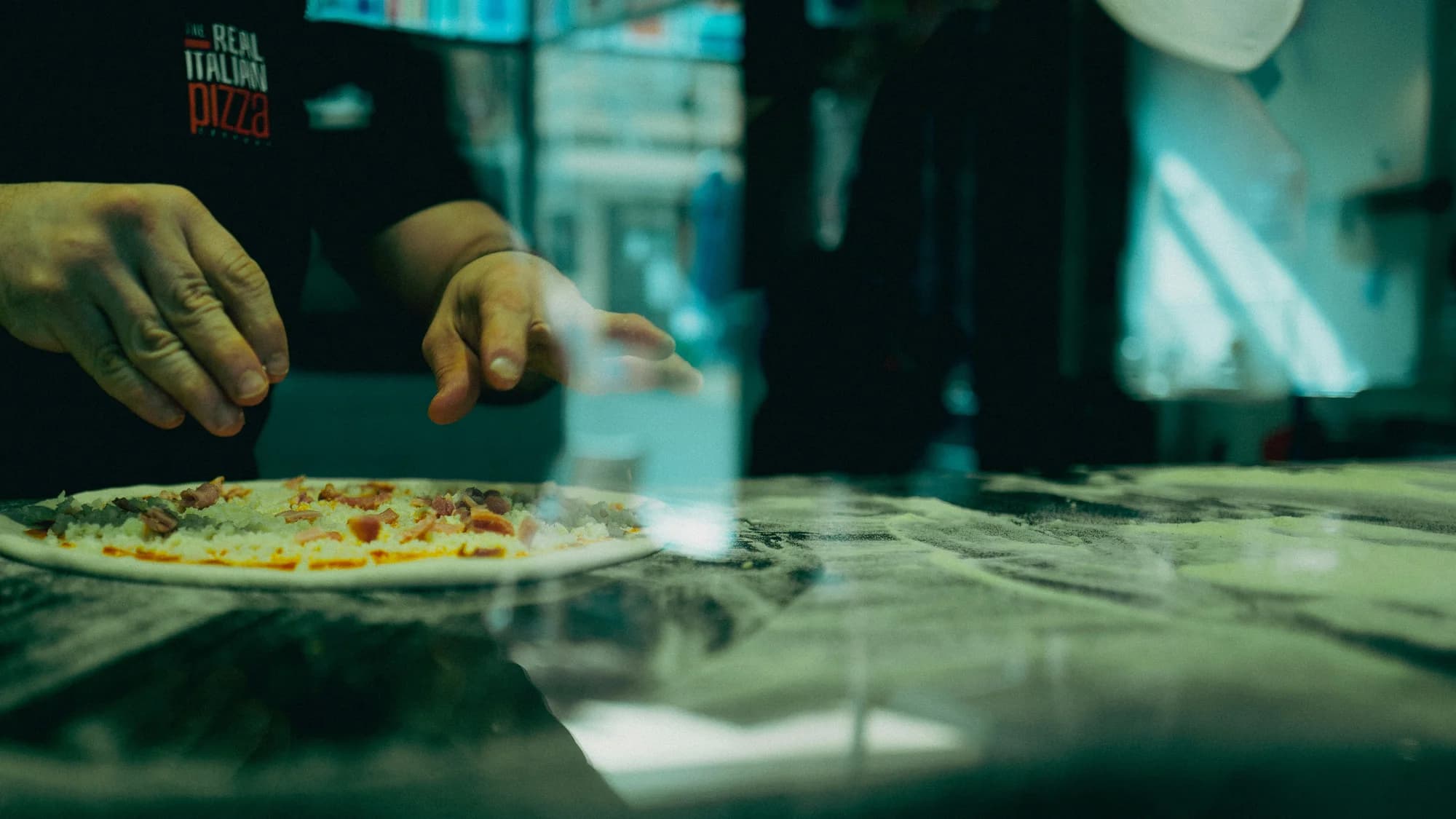 Pizza toppings being added — representative photo, not taken at Paesano Pizza — Southside