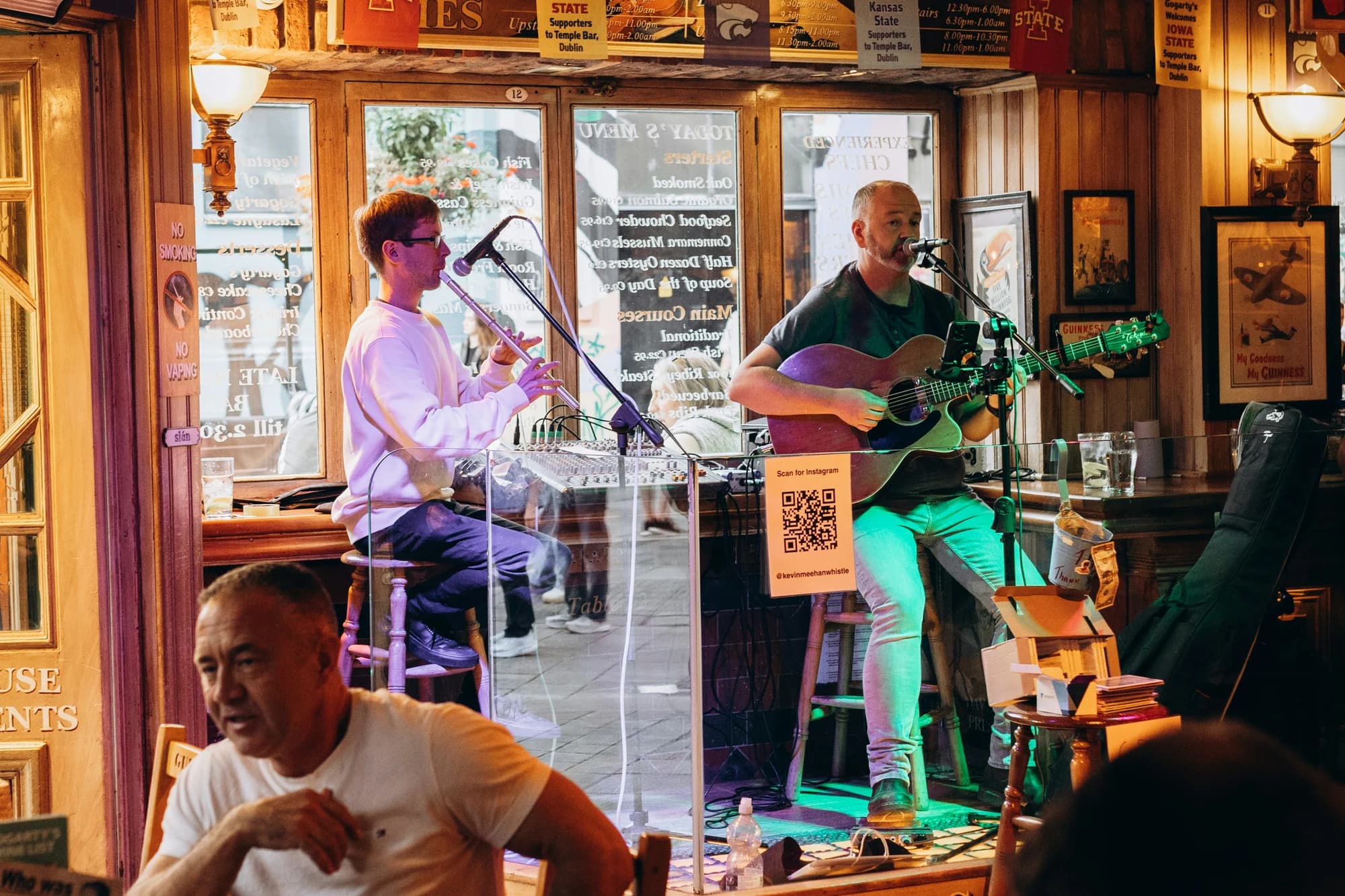 Two musicians play guitar and wind instrument in a pub — representative photo, not taken at Scotia Bar