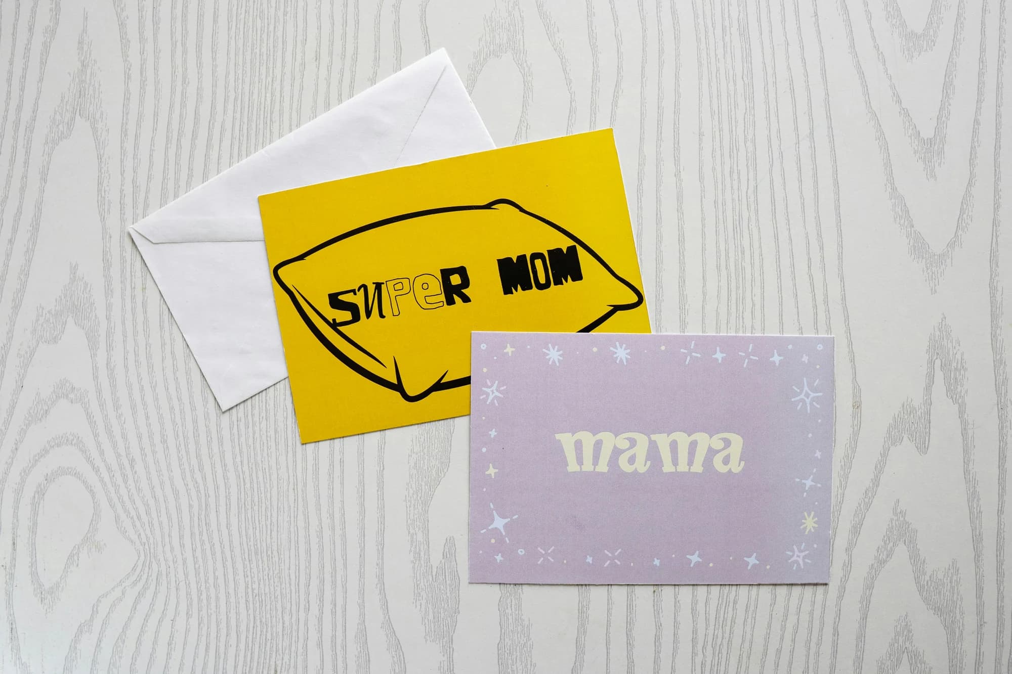 Two greeting cards with envelopes on a wooden surface. — representative photo, not taken at Scribbler — Buchanan Galleries