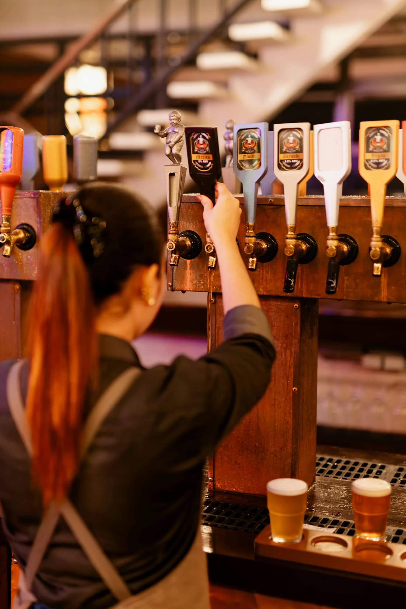 Bartender selecting a beer tap at a bar. — representative photo, not taken at The Allison Arms