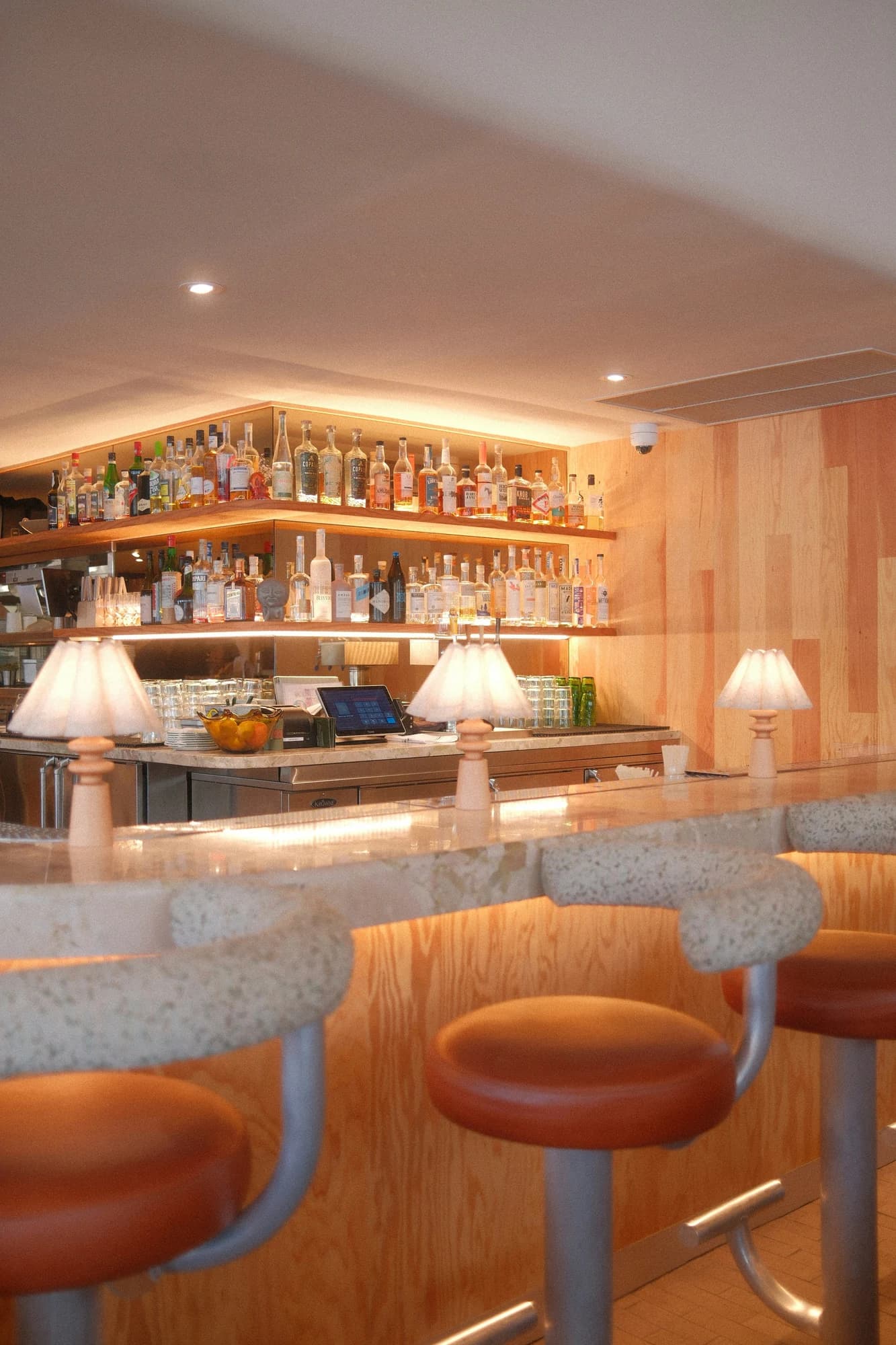 Bar with rows of liquor bottles and stools — representative photo, not taken at The Last Bookstore
